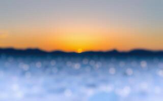 Colorful sunset over calm water with blurred horizon and distant mountains in soft evening light photo