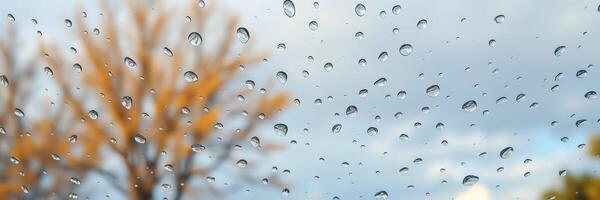 Raindrops on a window with blurred background of autumn trees during overcast weather photo