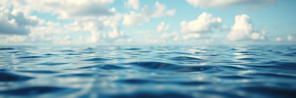 Calm waters under a bright sky with fluffy clouds reflecting softly on the surface during midday photo