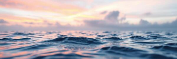 Beautiful sunset over calm ocean waves with soft clouds in the background reflecting warm colors photo