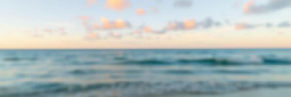 Beautiful sunset over calm ocean waters with gentle waves and pastel-colored clouds at twilight photo
