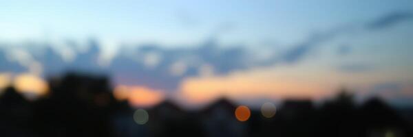 Colorful sunset casts a gradient across the sky with silhouetted buildings in the foreground during evening hours photo