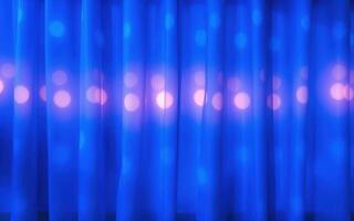 Light reflections and blurred blue curtains create an artistic backdrop for an event during the evening in a cozy venue photo