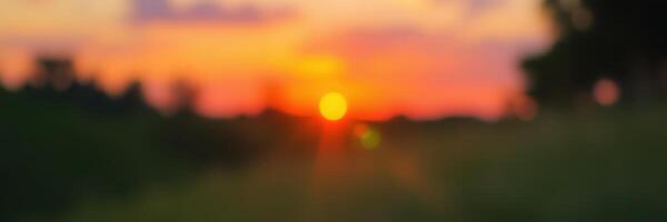 Beautiful sunset over a serene landscape with vibrant colors and soft silhouettes of trees photo