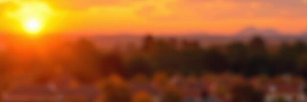 Sunset casts warm hues over landscape featuring trees and distant mountains during a tranquil evening photo