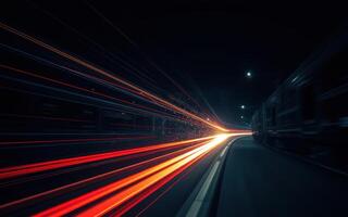 Train speeds through a nighttime station creating bright light trails along the tracks photo