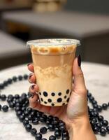 Delicious bubble tea served in a clear cup with a hand holding it against a stylish background photo