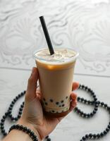 Enjoying a refreshing bubble tea with pearls in hand against a beautifully patterned backdrop photo