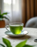 Fresh green tea served in a transparent cup on a table with soft morning light streaming through a window photo