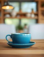 Blue ceramic cup on a saucer positioned on a wooden table in a cozy cafe setting during daylight photo