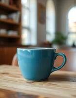 Vibrant teal cup resting on a wooden table in a cozy, sunlit cafe during a calm afternoon photo