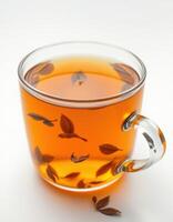 Freshly brewed herbal tea in clear glass mug with floating leaves showcasing a calming beverage experience photo