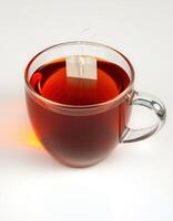 Enjoying a warm cup of herbal tea with a tea bag steeping in a transparent glass mug photo