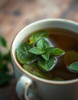 Fresh mint tea in a delicate cup with vibrant green leaves floating on top enjoying a cozy moment photo