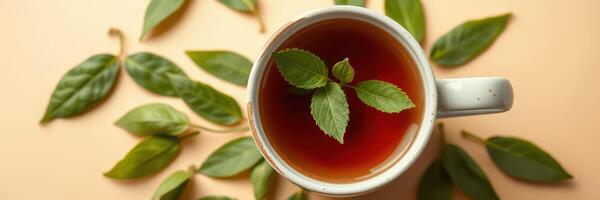 Freshly brewed herbal tea with mint leaves arranged artistically on a peach background photo