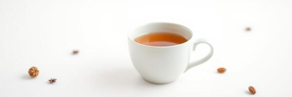 Warm cup of spiced tea sitting on a simple white table with scattered spices nearby photo