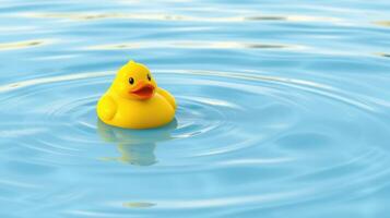 Yellow rubber duck floating on calm blue water reflecting soft ripples during sunny daylight photo