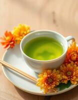 Delicate green tea served in a white cup surrounded by vibrant orange flowers photo