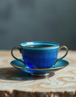 Elegant blue tea cup and saucer on a patterned table, showcasing intricate design details in soft light photo