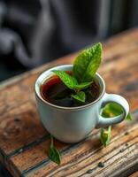 Fresh mint tea served in a small white cup on a rustic wooden table close to a blurred background photo
