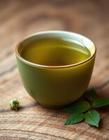 Delicate green tea in a ceramic cup on a rustic wooden table with fresh leaves nearby photo