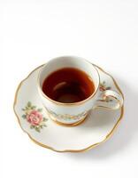 Elegant porcelain cup and saucer with tea on a white background, showcasing a floral design and fine craftsmanship during afternoon tea photo