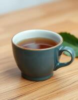 Warm cup of tea placed on a wooden table with leaf accents in a cozy indoor setting photo
