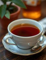 Warm cup of tea on a wooden table with a small plant in the background during a cozy afternoon at home photo