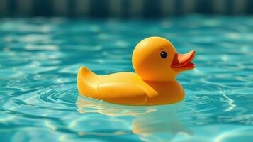 Bright yellow rubber duck floats serenely on a blue pool under the sun during summer photo