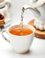 Warm tea being poured into a delicate cup in a cozy setting during afternoon tea time photo
