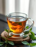 Herbal tea in a transparent cup with fresh mint leaves on a wooden coaster in a cozy setting photo