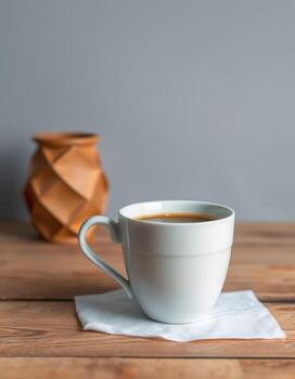 Warm beverage in a white cup on wooden table with a decorative vase in a cozy setting photo