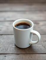 Coffee mug filled with hot beverage resting on a wooden table in a cozy setting during morning sunlight photo