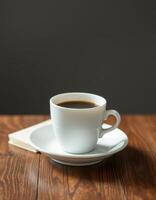 Warm cup of coffee on a wooden table next to a small notepad in a cozy indoor setting during the morning photo