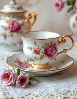 Delicate porcelain tea set with floral design and gold accents arranged on a lace tablecloth photo