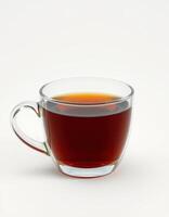 Warm cup of brewed black tea served in a clear glass mug against a plain background photo