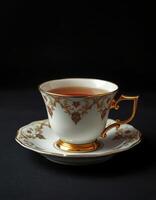 Elegant tea cup with gold detailing contains steaming beverage on a dark surface photo