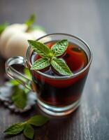 Mint tea served in a clear glass cup on a rustic wooden table with fresh mint leaves and a white pumpkin photo