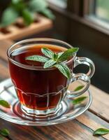 Warm cup of herbal tea with fresh mint leaves served on a wooden table near a window photo