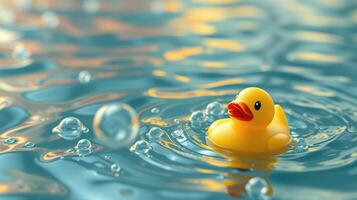 Bright yellow rubber duck floats on the shimmering blue water surrounded by bubbles during a sunny day photo