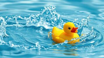 Bright yellow rubber duck floating in clear blue water creating splashes on a sunny day at a pool photo