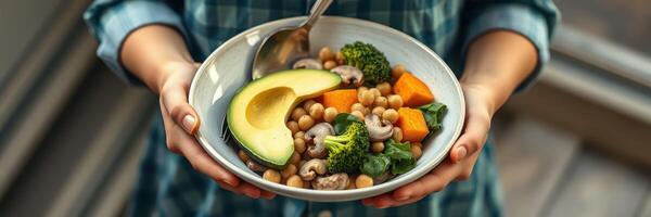 Fresh vegetable and chickpea salad with avocado served by a person in a cozy kitchen setting photo