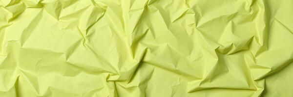 Crumpled green paper texture highlights unique patterns and shadows from natural light during the day photo