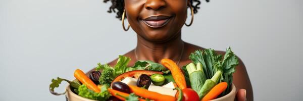 Woman holding a bowl of fresh vegetables with a joyful expression in a bright setting photo