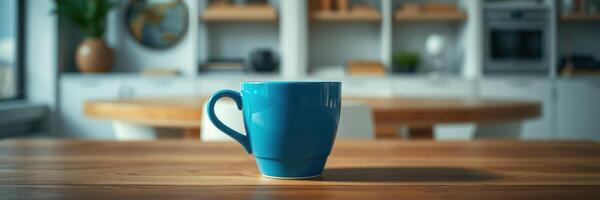 Blue coffee cup on wooden table in a modern kitchen with natural light streaming through large windows photo