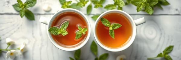 Fresh mint tea served in white cups on a wooden table surrounded by mint leaves and flowers photo