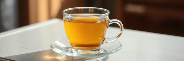Warm herbal tea in a clear glass cup served on a small saucer on a wooden table in a cozy setting photo
