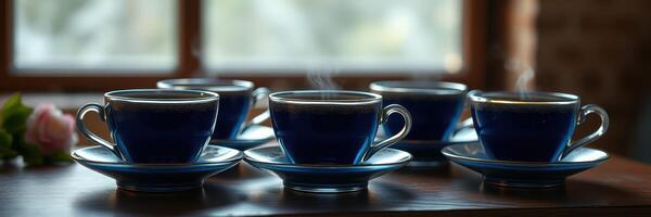 Five steaming blue cups of coffee arranged on a wooden table near a window with soft natural light photo