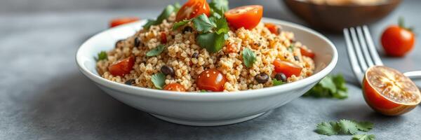 Fresh couscous salad with cherry tomatoes and herbs served on a white plate with a fork nearby photo