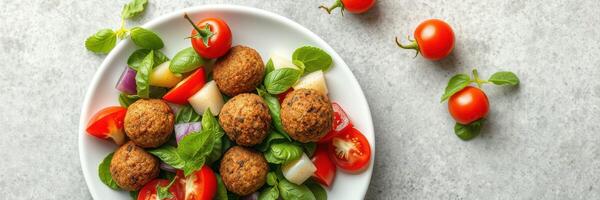 Healthy falafel salad with fresh vegetables and cherry tomatoes served on a white plate photo